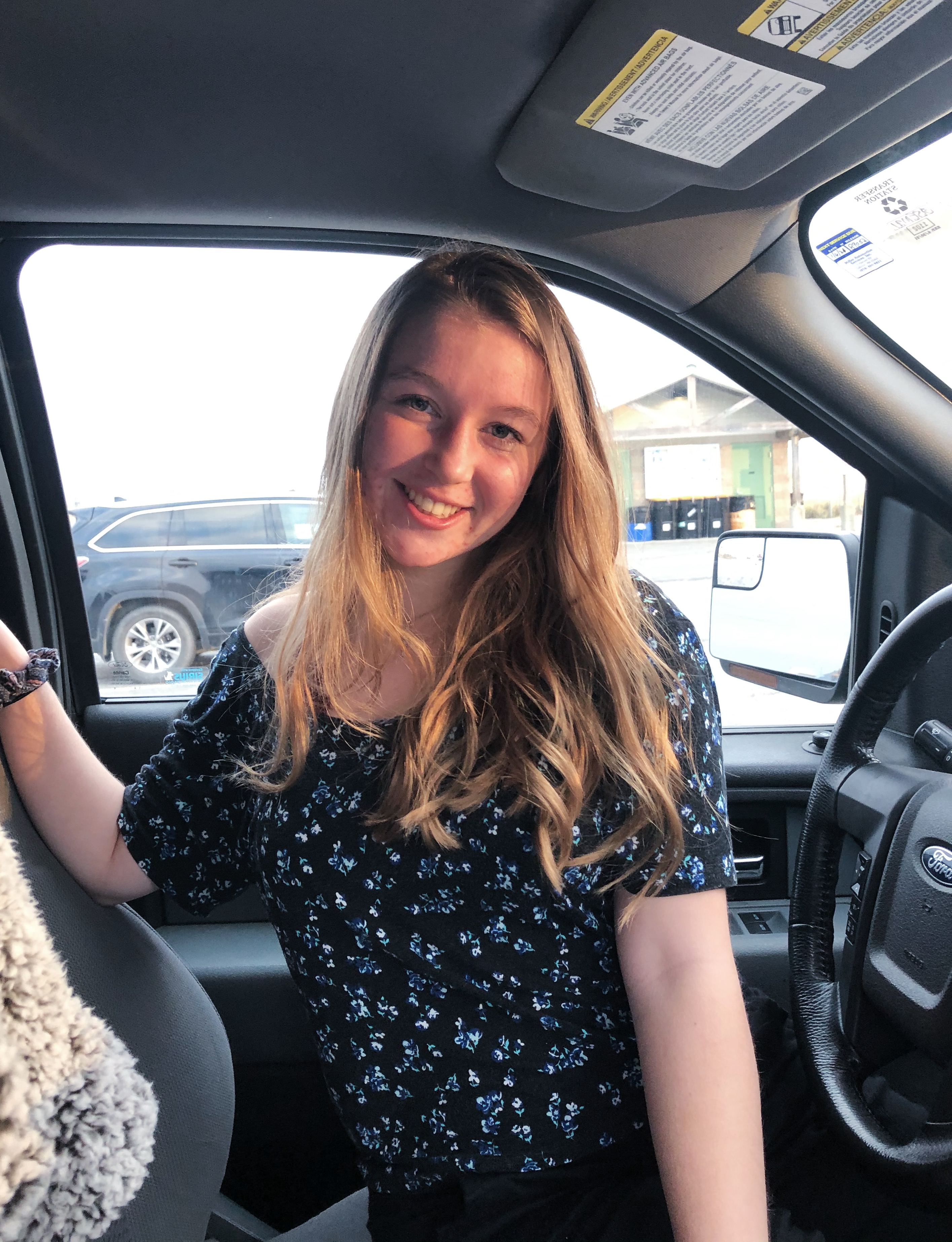 image of Sydney, in a blue shirt smiling at the camera